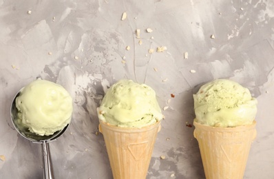Photo of Delicious pistachio ice cream in wafer cones on light grey table, flat lay. Space for text