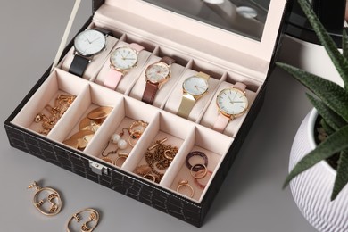 Photo of Elegant jewelry box with expensive wristwatches and beautiful bijouterie on grey table
