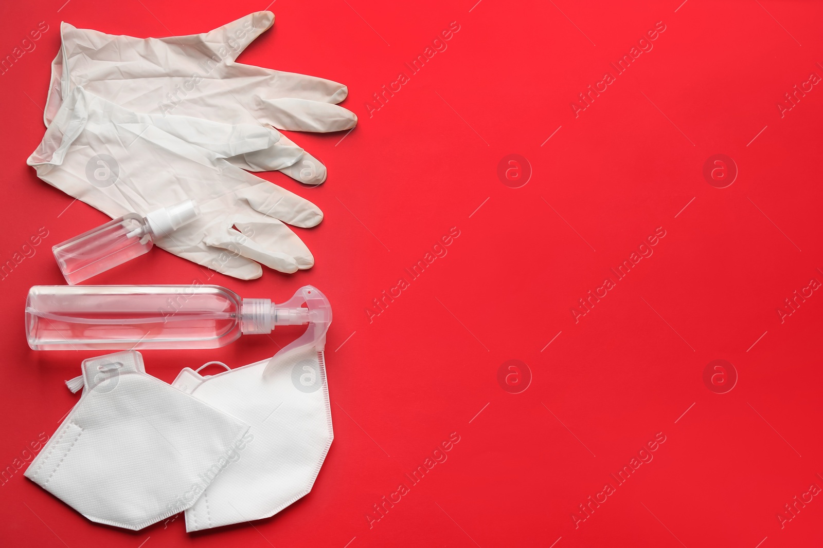 Photo of Flat lay composition with medical gloves, masks and hand sanitizers on red background. Space for text