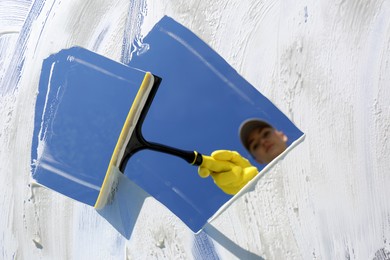 Photo of Woman cleaning glass with squeegee on sunny day