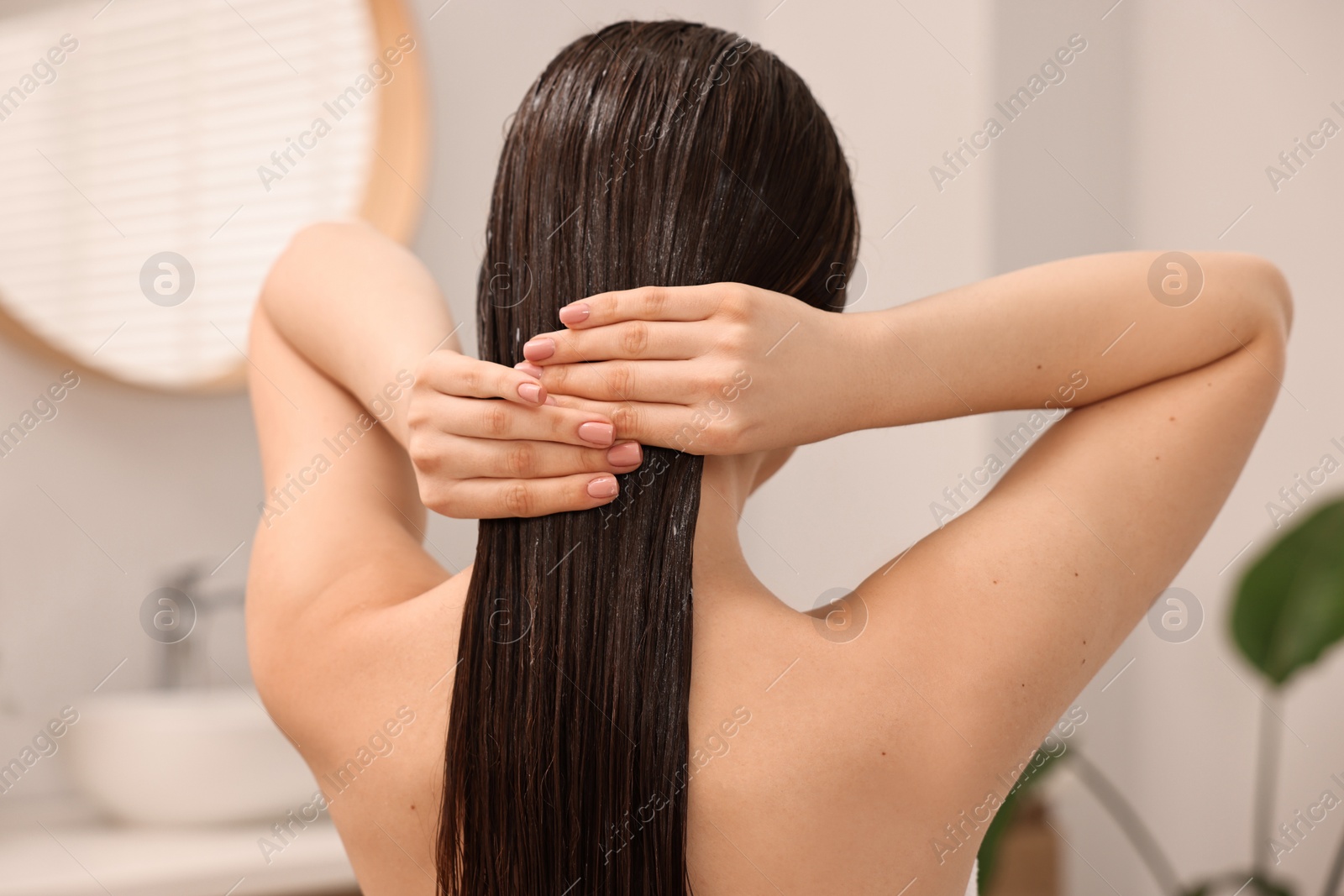 Photo of Woman applying hair mask in bathroom, back view