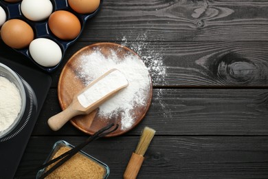 Flat lay composition with baking powder and products on black wooden table. Space for text