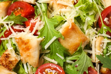 Photo of Delicious Caesar salad with fresh ingredients as background, closeup