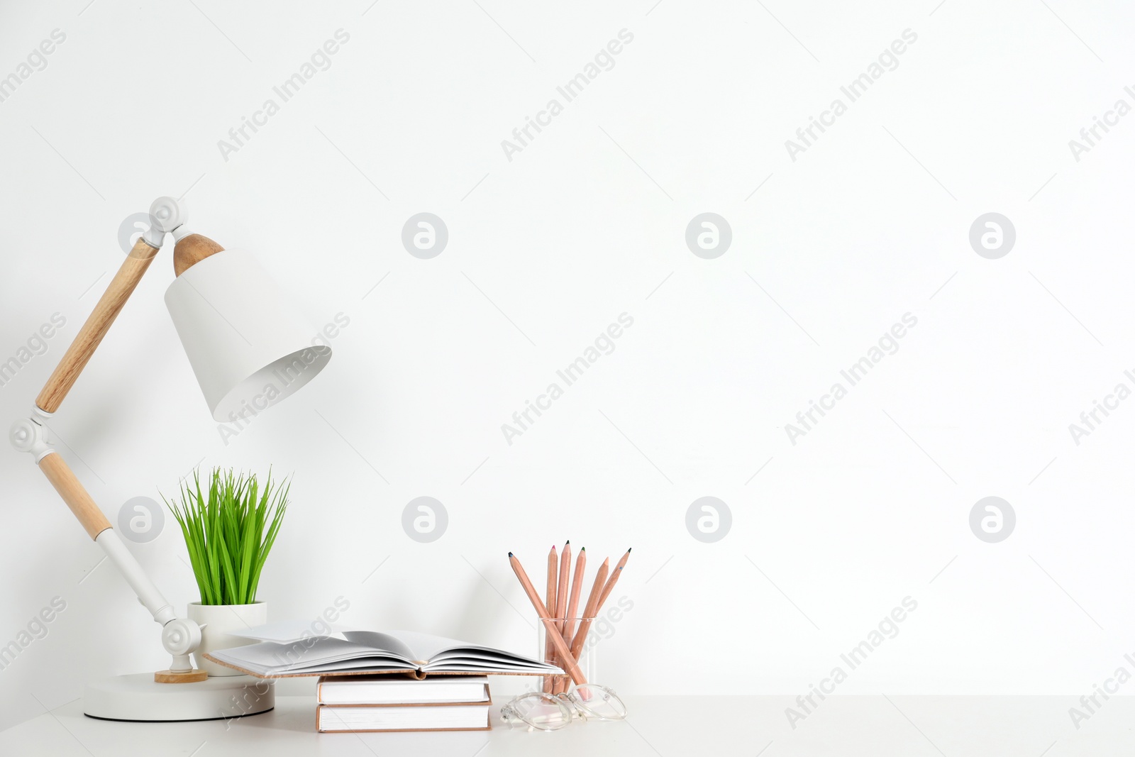 Photo of Comfortable workplace with white desk near wall. Space for text