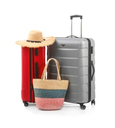 Photo of Packed suitcase with hat and hand-luggage on white background