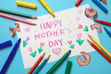 Photo of Flat lay composition with handmade greeting card for Mother's Day on blue background