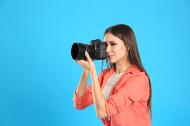 Photo of Professional photographer working on light blue background in studio. Space for text