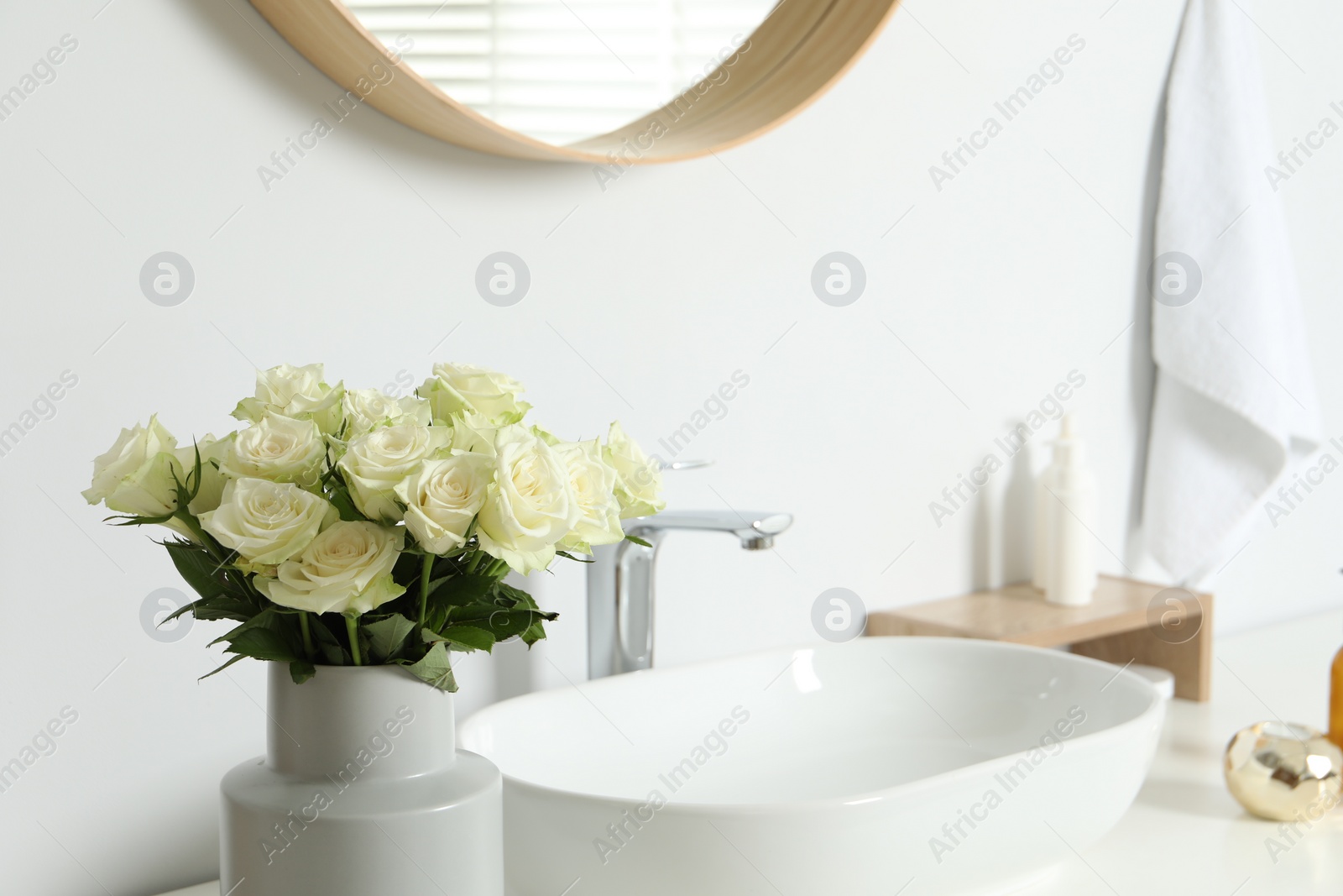 Photo of Vase with beautiful white roses near sink in bathroom