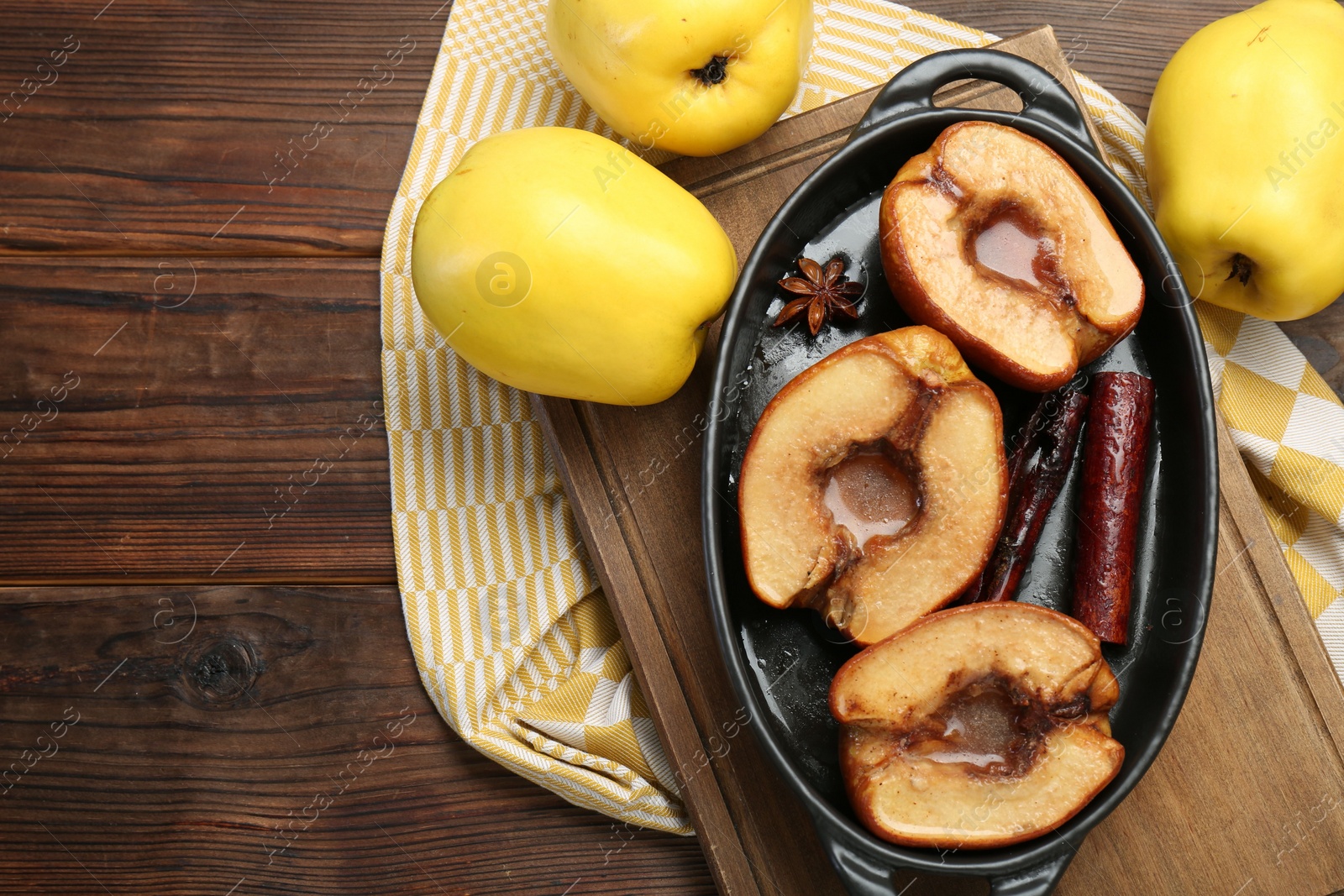 Photo of Tasty baked quinces with spices and honey in dish on wooden table, flat lay. Space for text