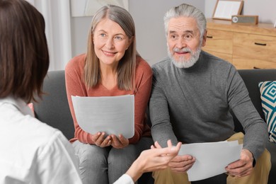 Insurance agent consulting elderly couple about pension plan in room