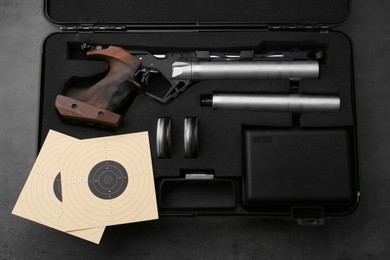 Photo of Case with sport pistol and accessories on black table, top view. Professional gun