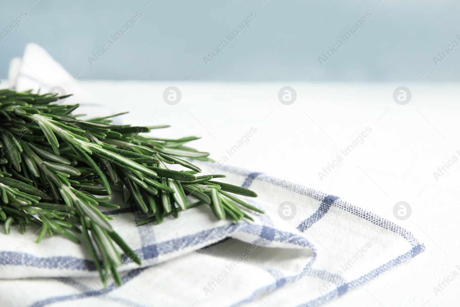 Photo of Fresh green rosemary and napkin on table. Space for text