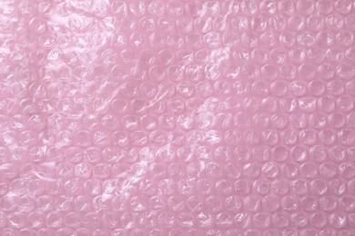 Transparent bubble wrap on pink background, top view