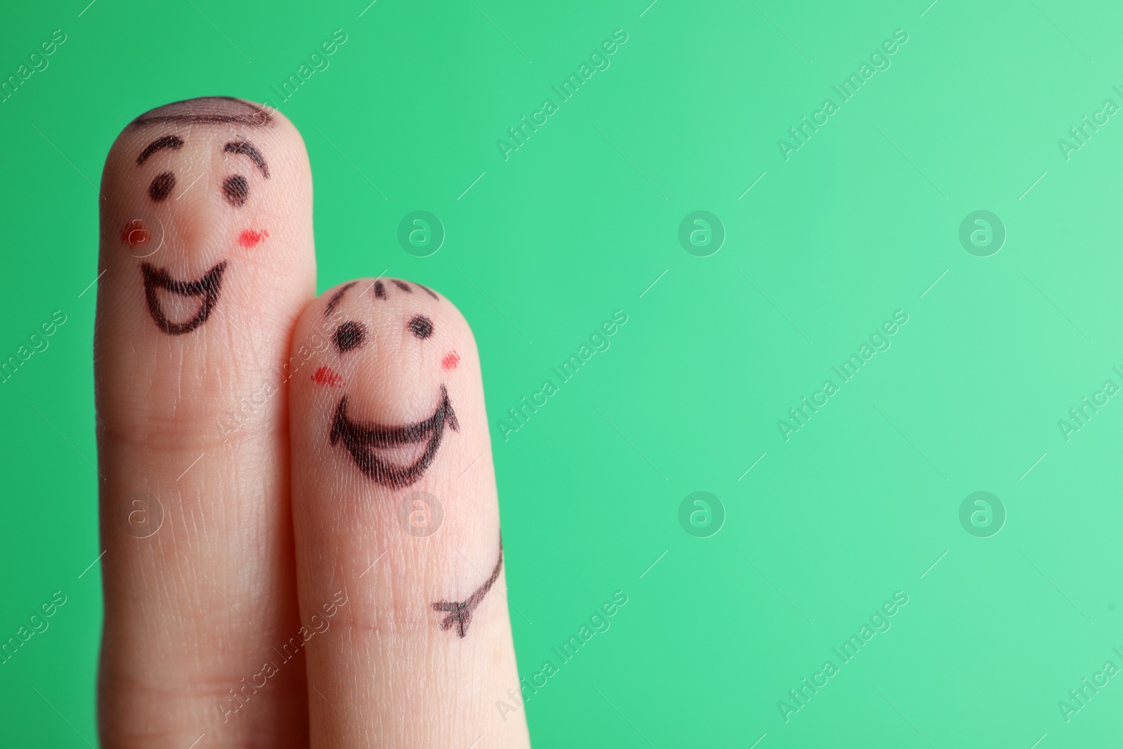 Photo of Two fingers with drawings of happy faces on green background, space for text. Spending time together