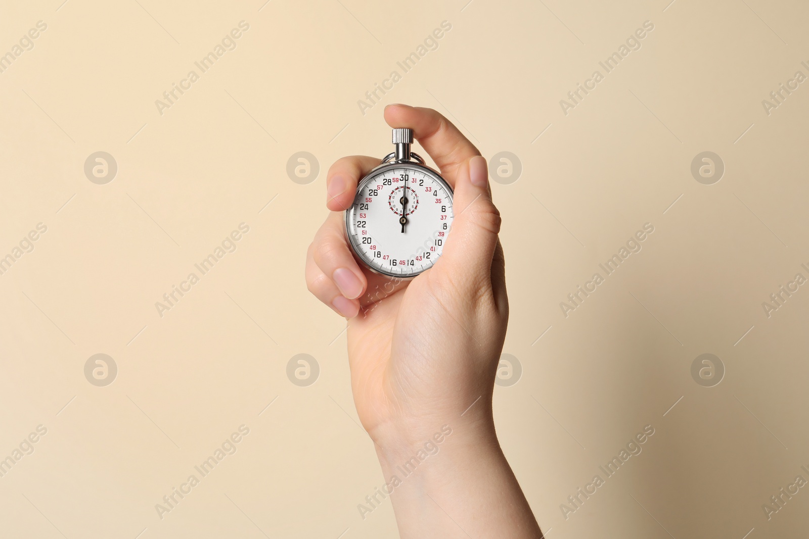 Photo of Woman holding vintage timer on beige background, closeup