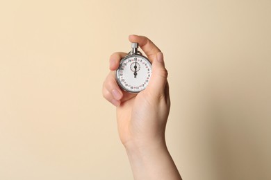 Woman holding vintage timer on beige background, closeup