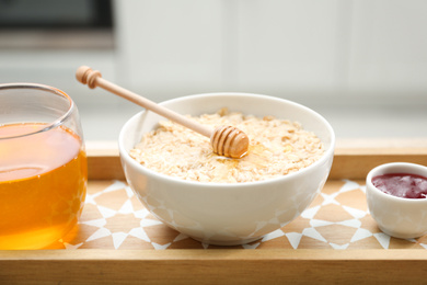 Bowl of tasty oatmeal with honey on table