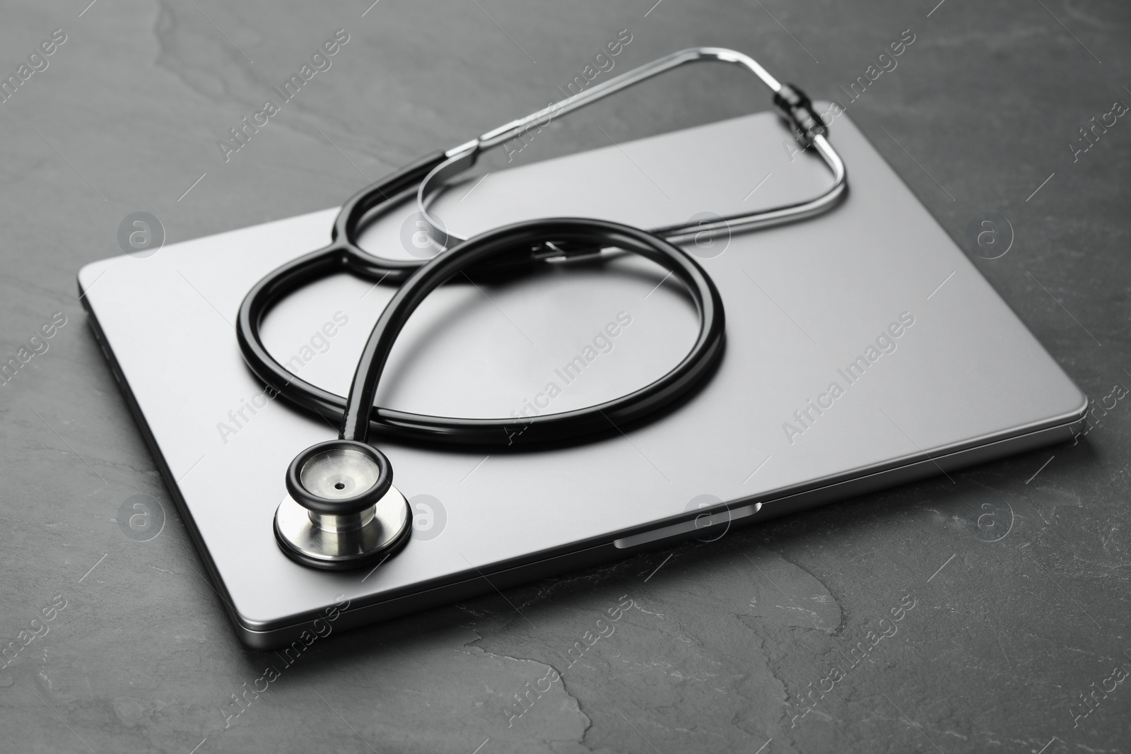 Photo of Modern laptop and stethoscope on black table