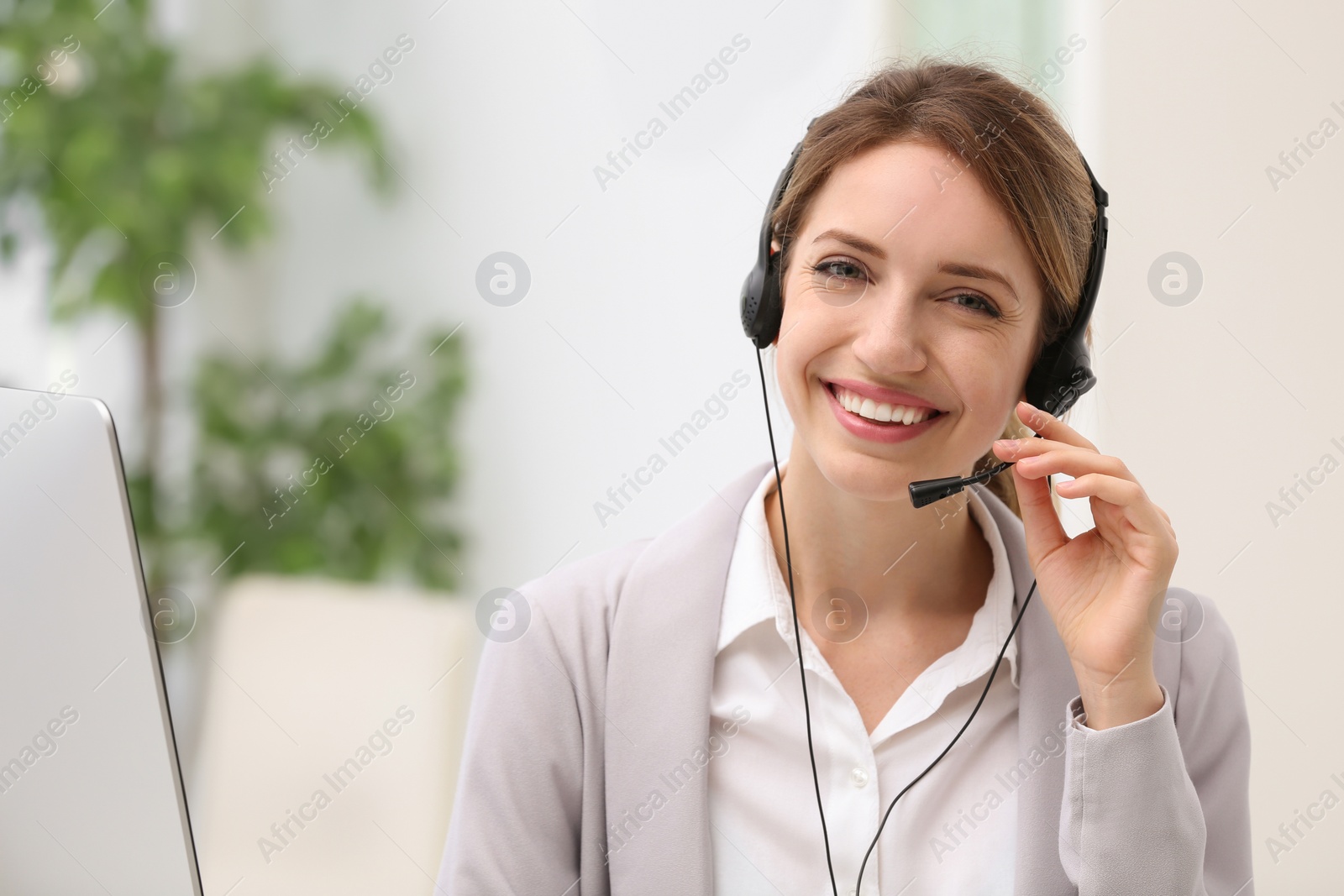 Photo of Young female receptionist with headset in office