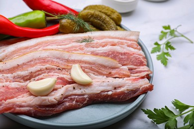 Tasty pork fatback served on white marble table, closeup