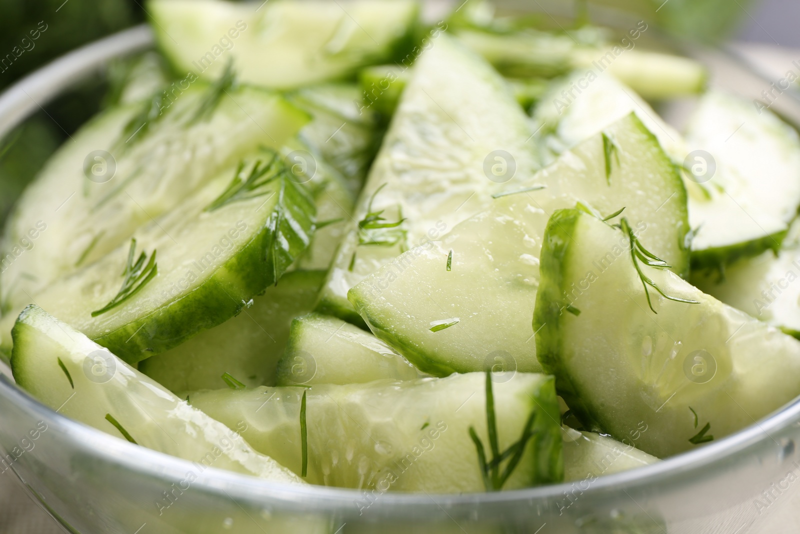 Photo of Cut cucumber with dill in glass bowl, closeup