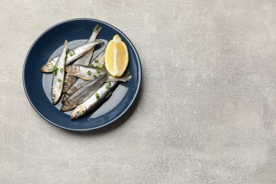 Photo of Fresh raw sprats, green onion and cut lemon on grey table, top view. Space for text