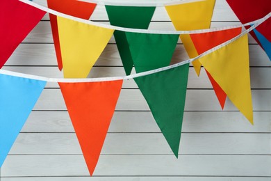 Photo of Buntings with colorful triangular flags on white wooden background