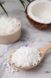 Coconut flakes in wooden spoon on white marble table