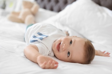 Photo of Adorable little baby lying on bed at home