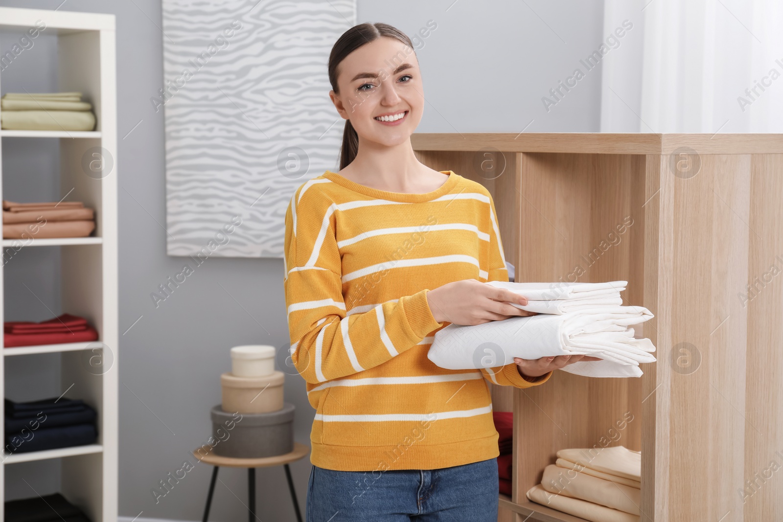 Photo of Smiling young woman with bed linens in shop