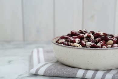 Photo of Bowl with dry kidney beans on table, closeup. Space for text