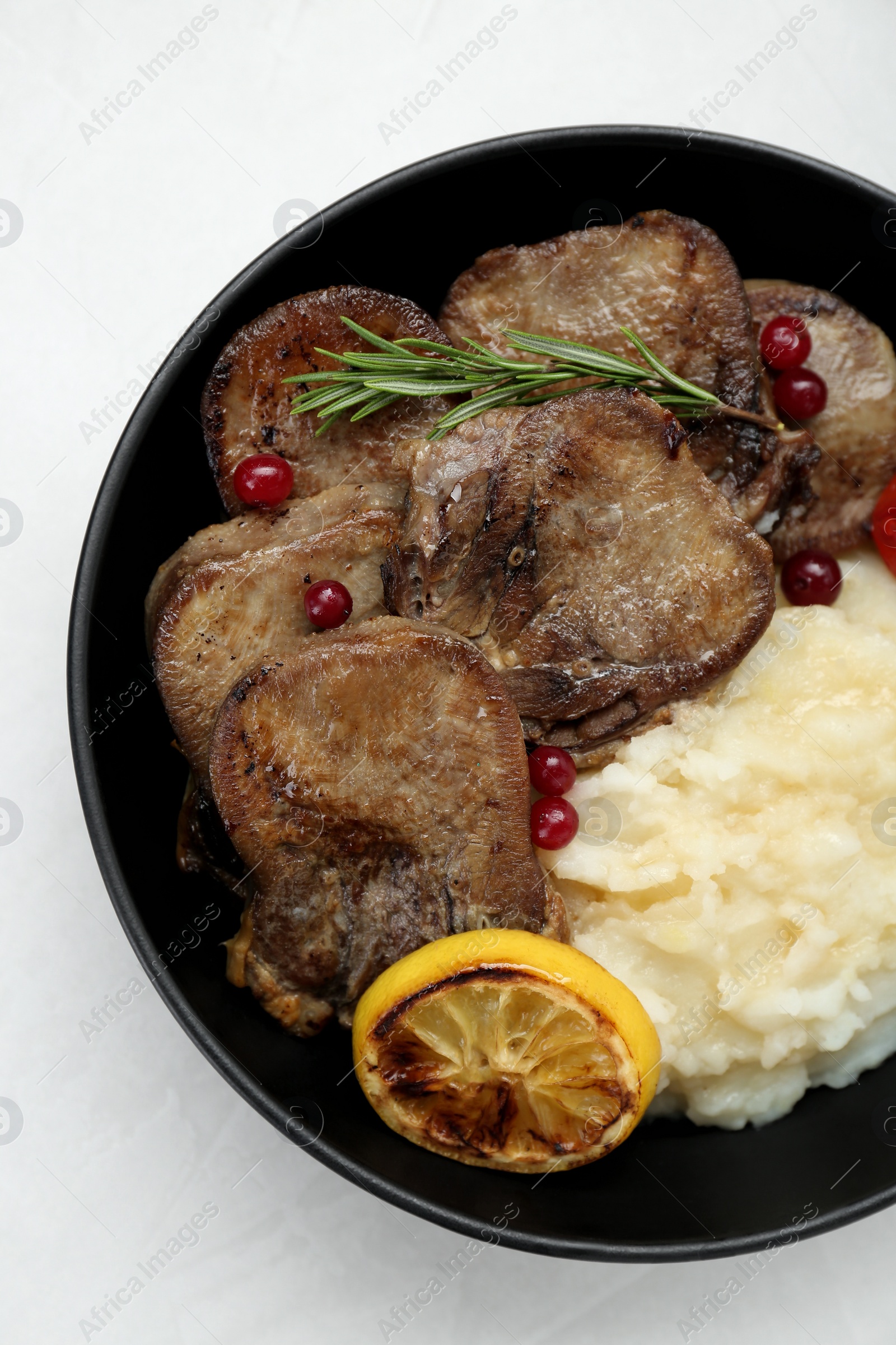 Photo of Tasty beef tongue pieces, berries, lemon, rosemary and mashed potatoes on white background, top view