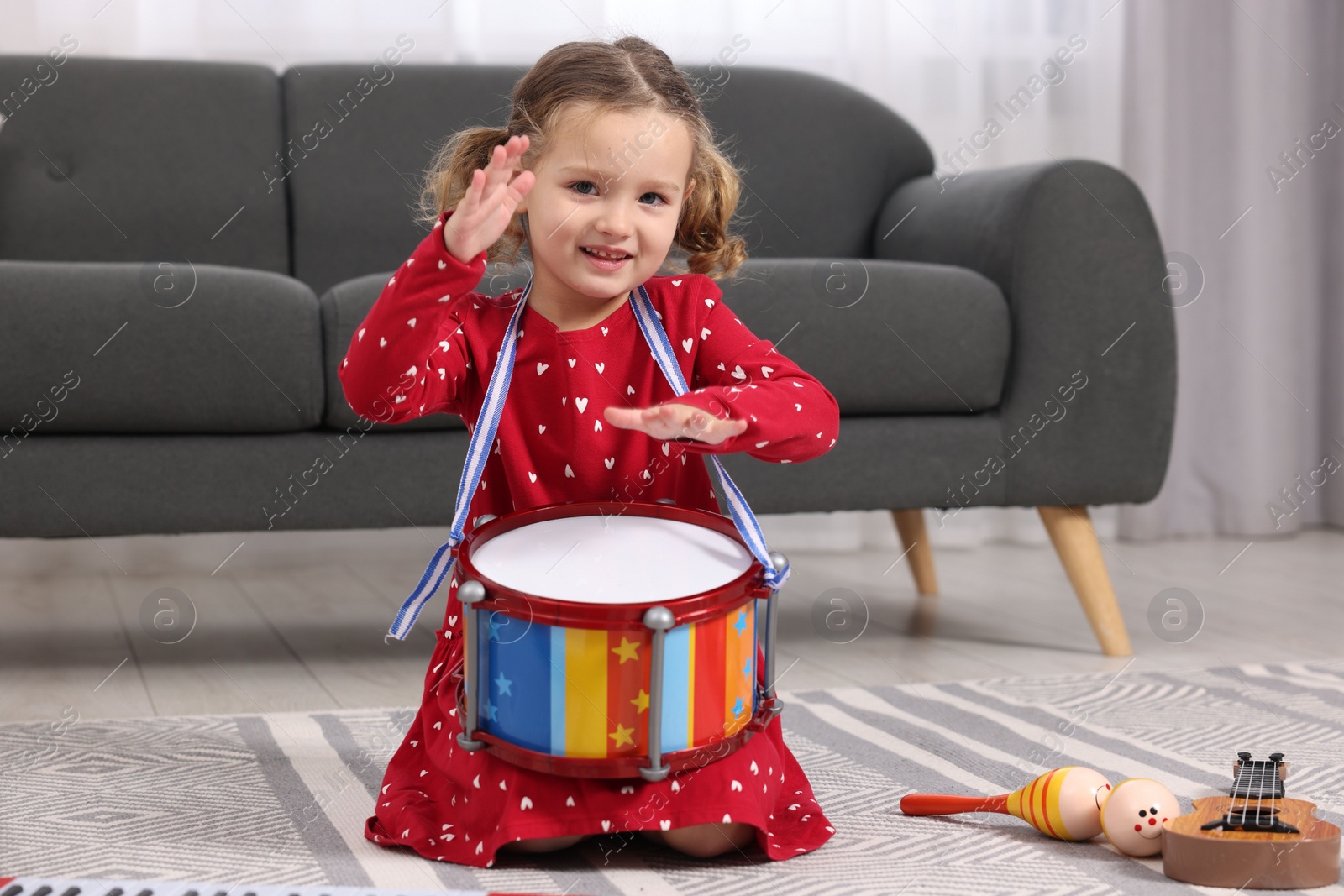 Photo of Little girl playing toy drum at home