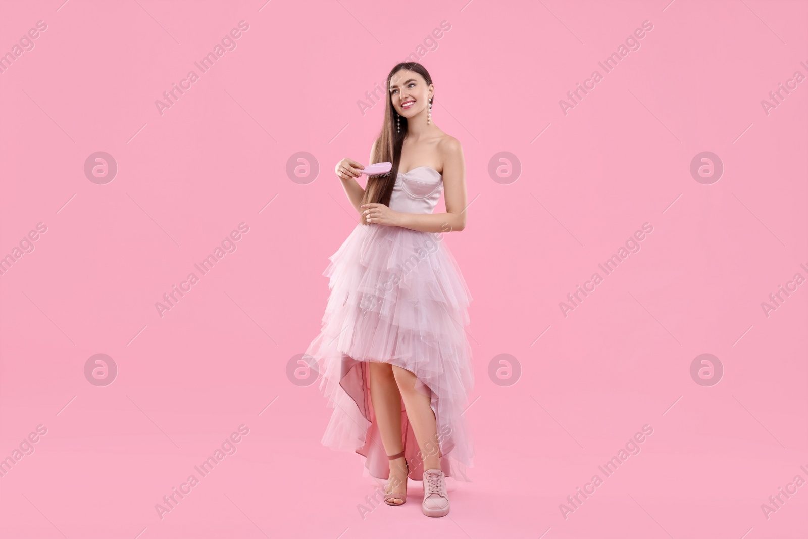 Photo of Woman wearing high heeled shoe and sneaker on pink background. Glamour vs comfort