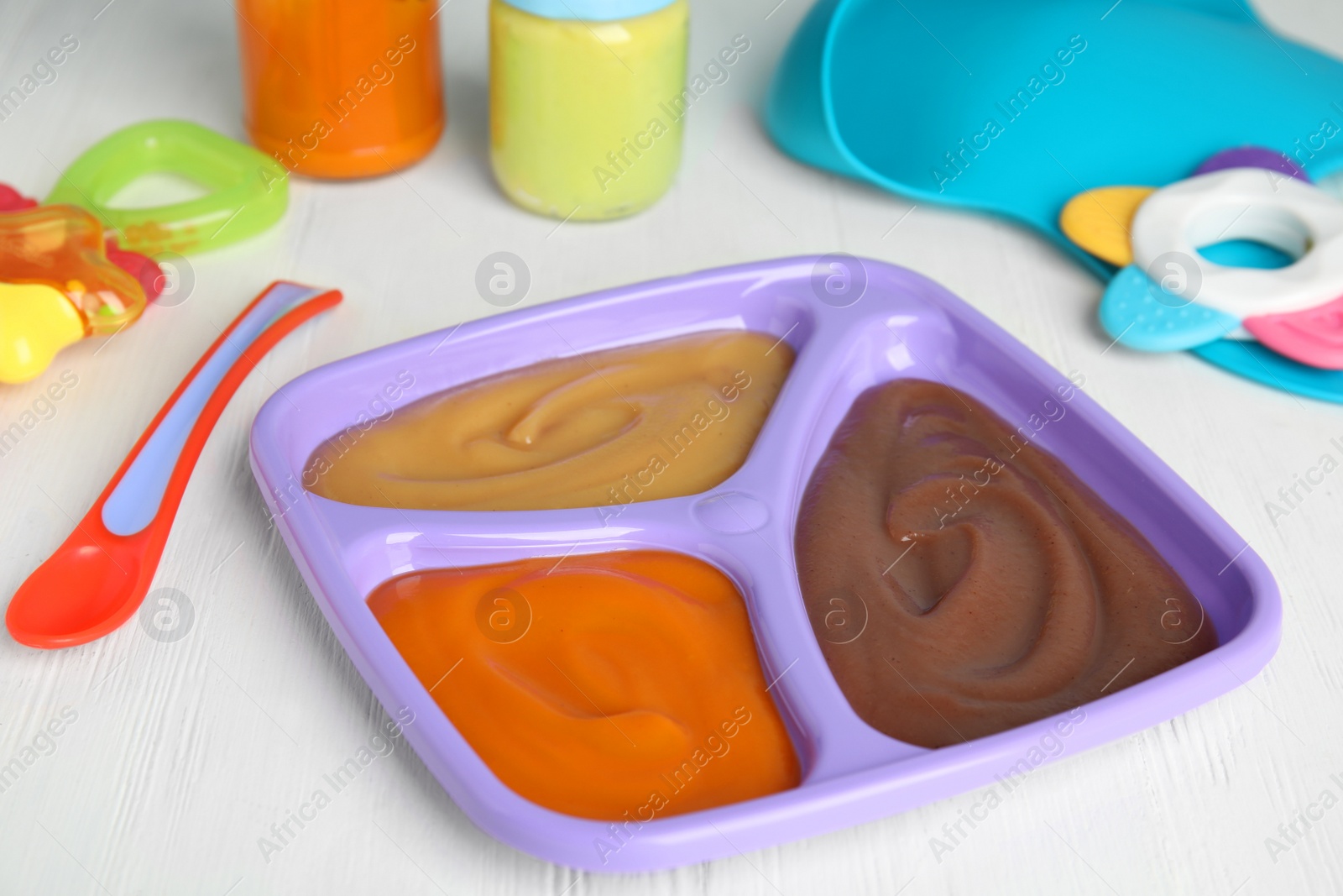 Photo of Healthy baby food and spoon on white wooden table