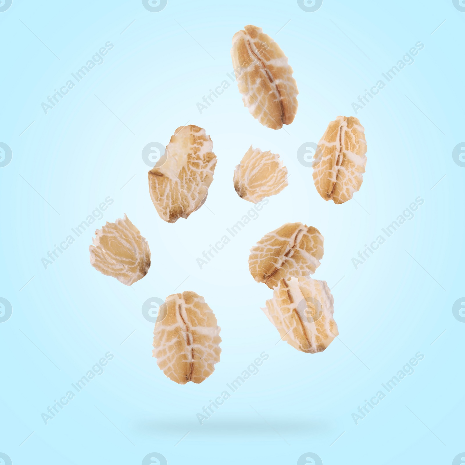 Image of Rolled oat flakes falling on light blue background