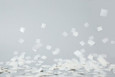 Photo of White confetti falling down on light grey background