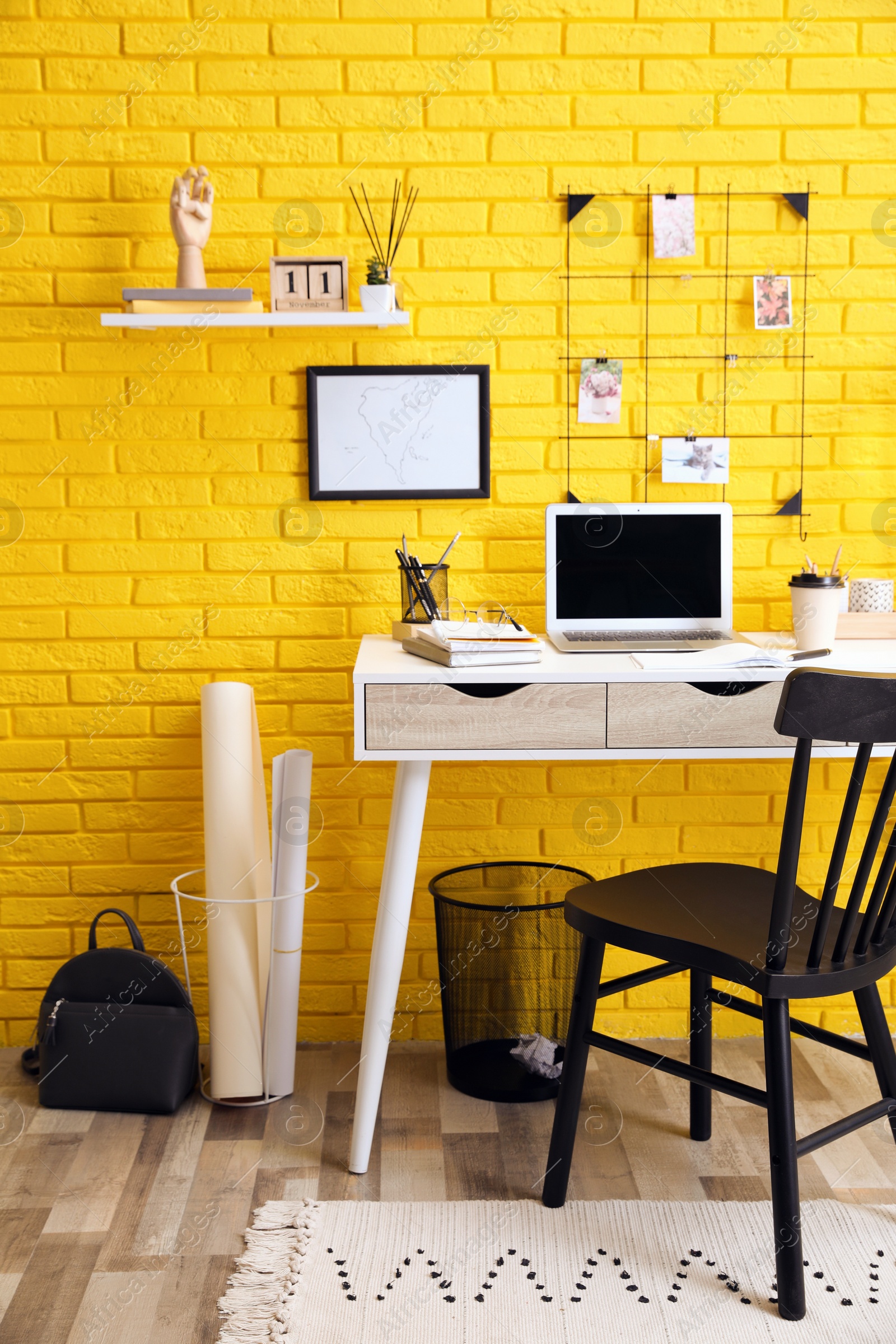 Photo of Stylish home office interior with comfortable workplace near yellow brick wall