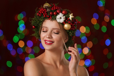 Photo of Beautiful young woman wearing Christmas wreath on blurred background. Bokeh effect