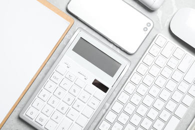 Photo of Calculator, smartphone and keyboard on grey table, flat lay. Tax accounting