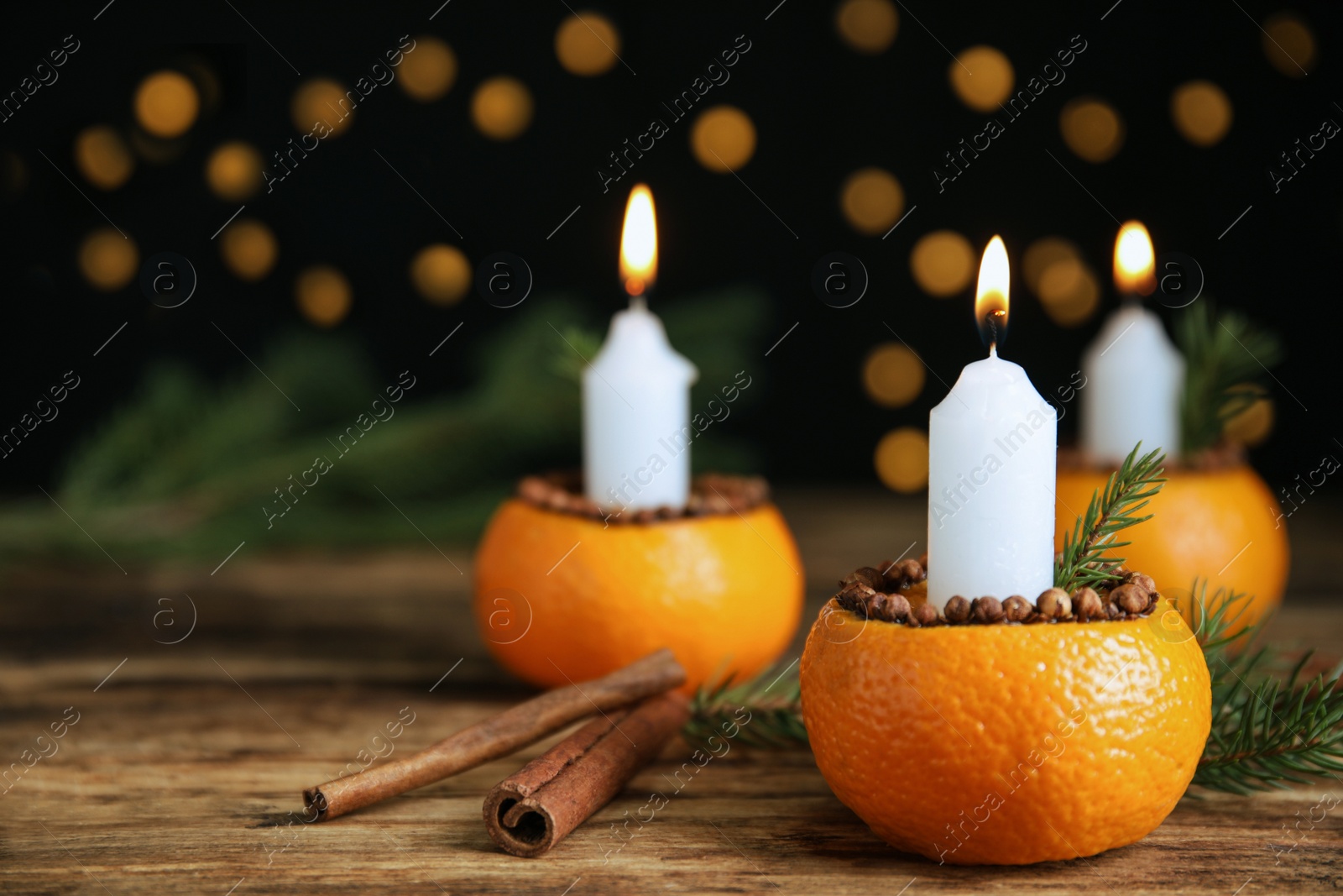 Photo of Burning candle in tangerine peel as holder on wooden table against black background, space for text