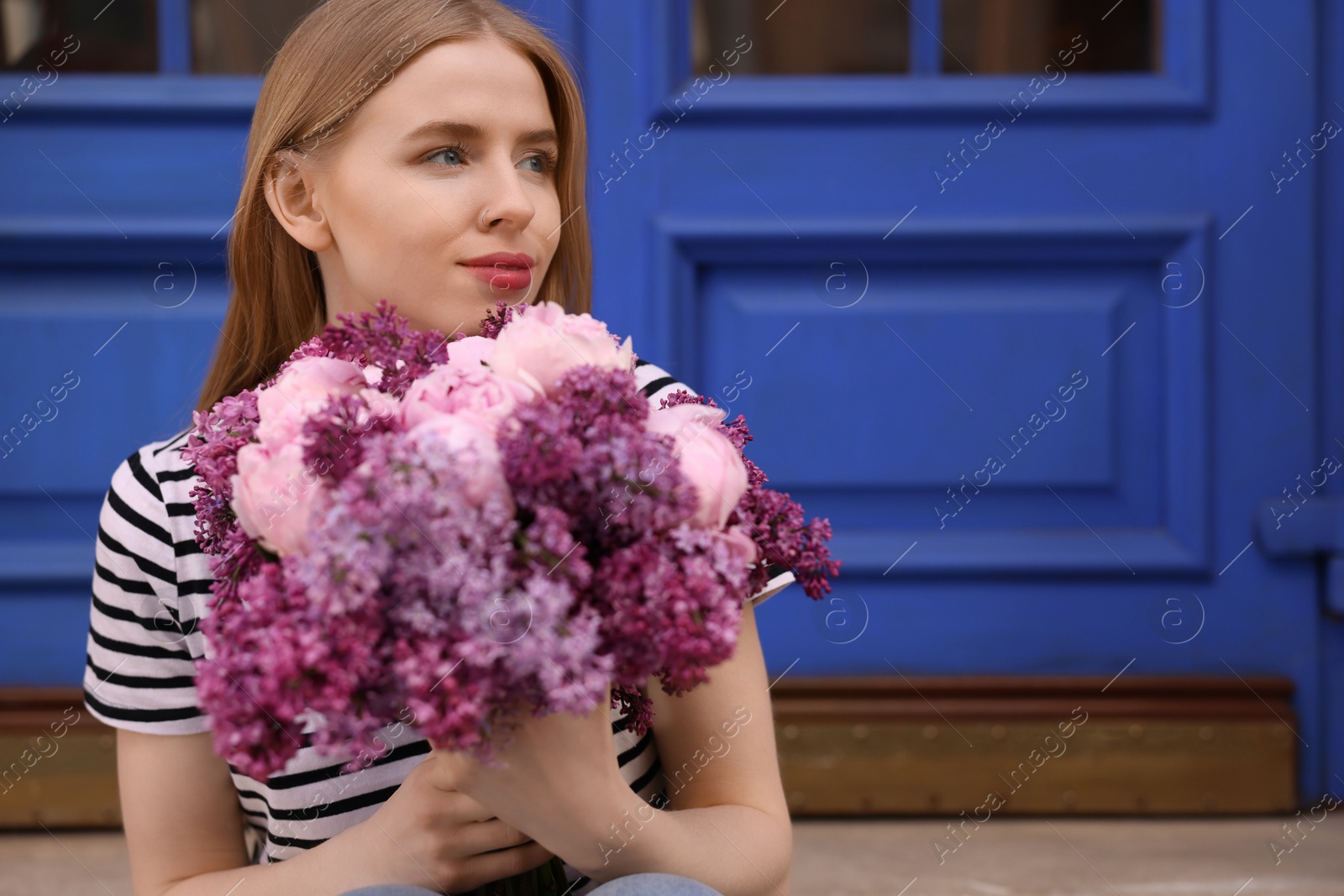 Photo of Beautiful woman with bouquet of spring flowers outdoors, space for text