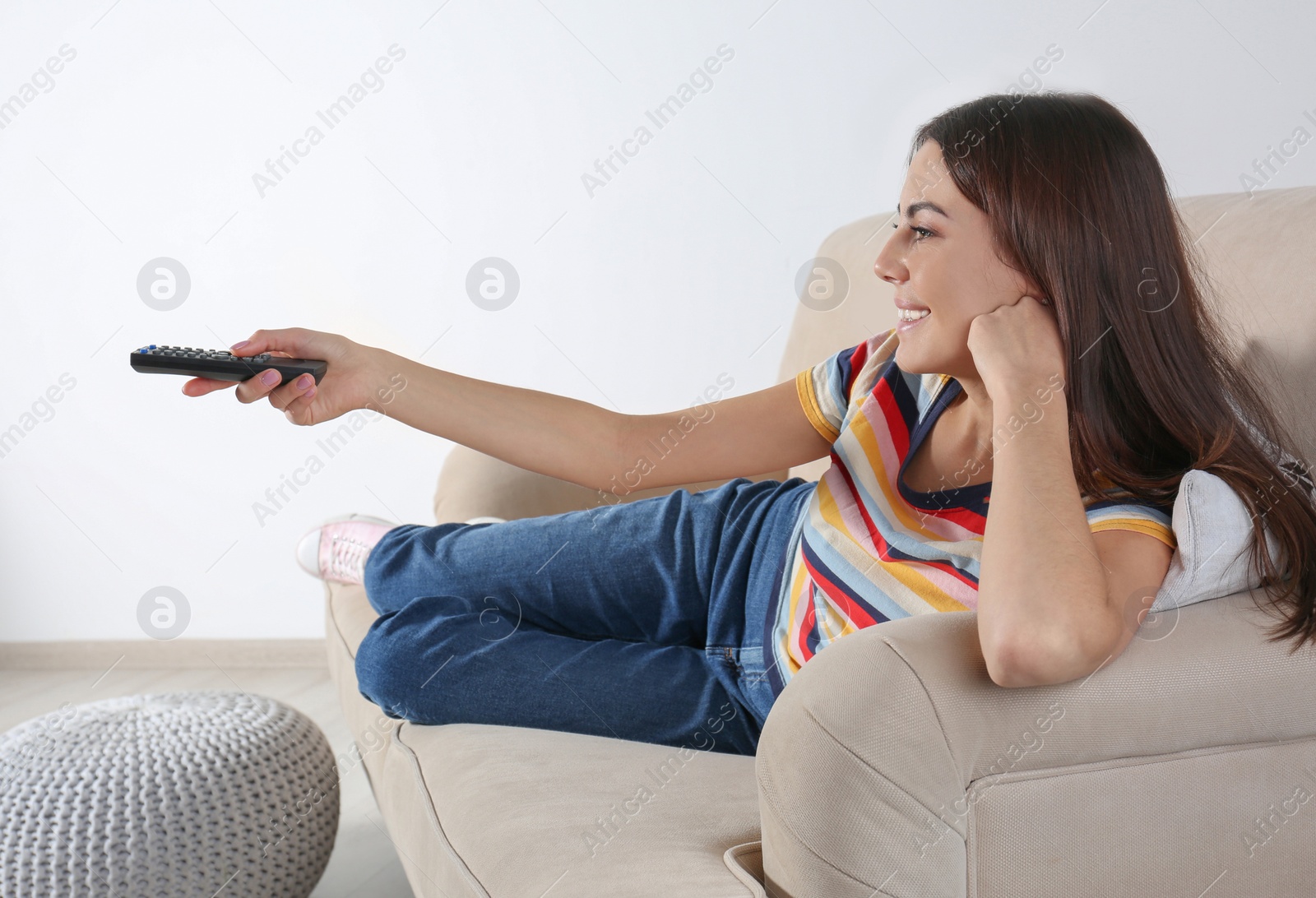 Photo of Beautiful young woman watching TV on sofa at home