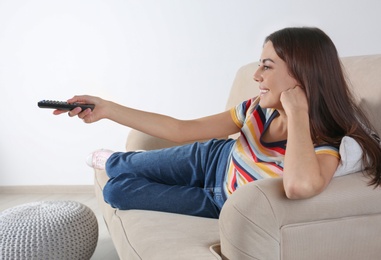 Beautiful young woman watching TV on sofa at home