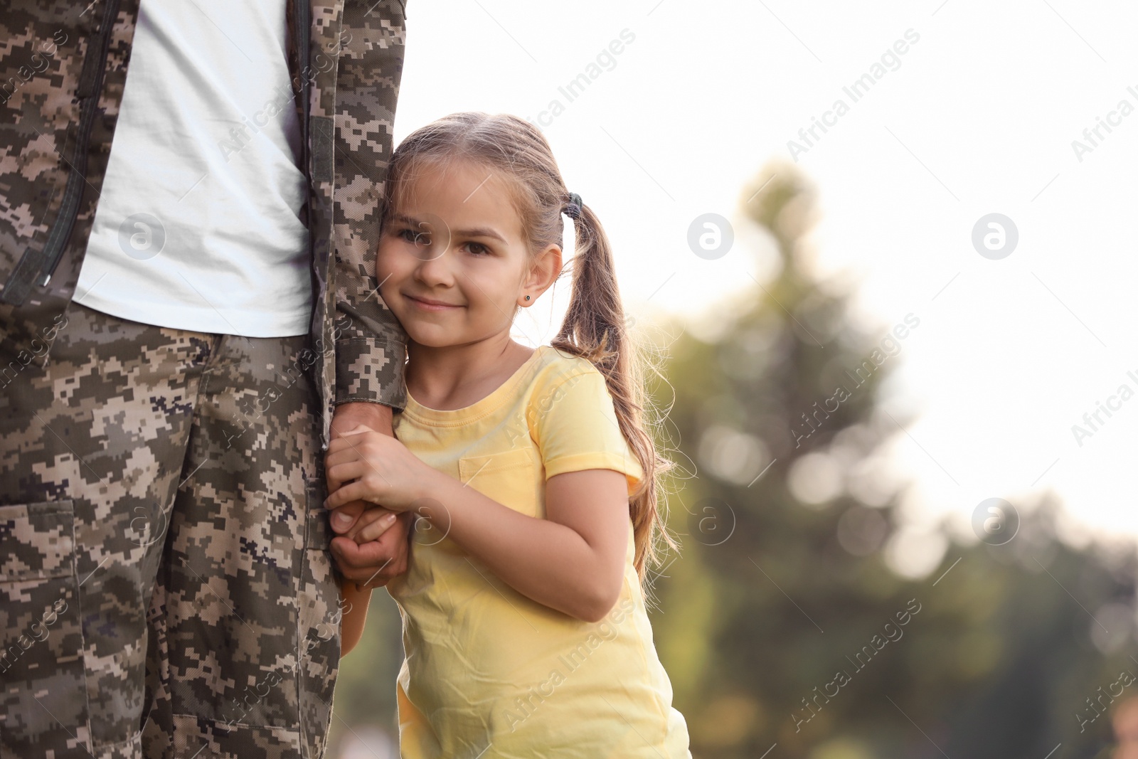 Photo of Little girl with her father in military uniform at sunny park