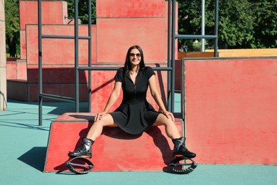 Photo of Woman with kangoo jumping boots sitting in workout park