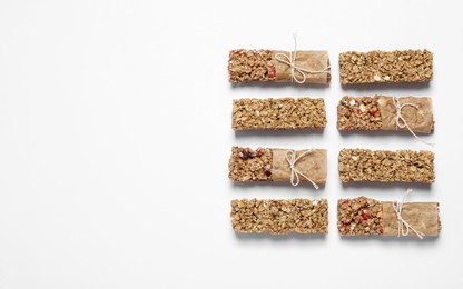 Photo of Different tasty granola bars on white background, flat lay. Space for text