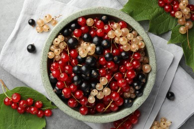 Different fresh ripe currants and green leaves on table, flat lay