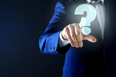 Image of Businessman using virtual screen with question mark symbol on dark background, closeup