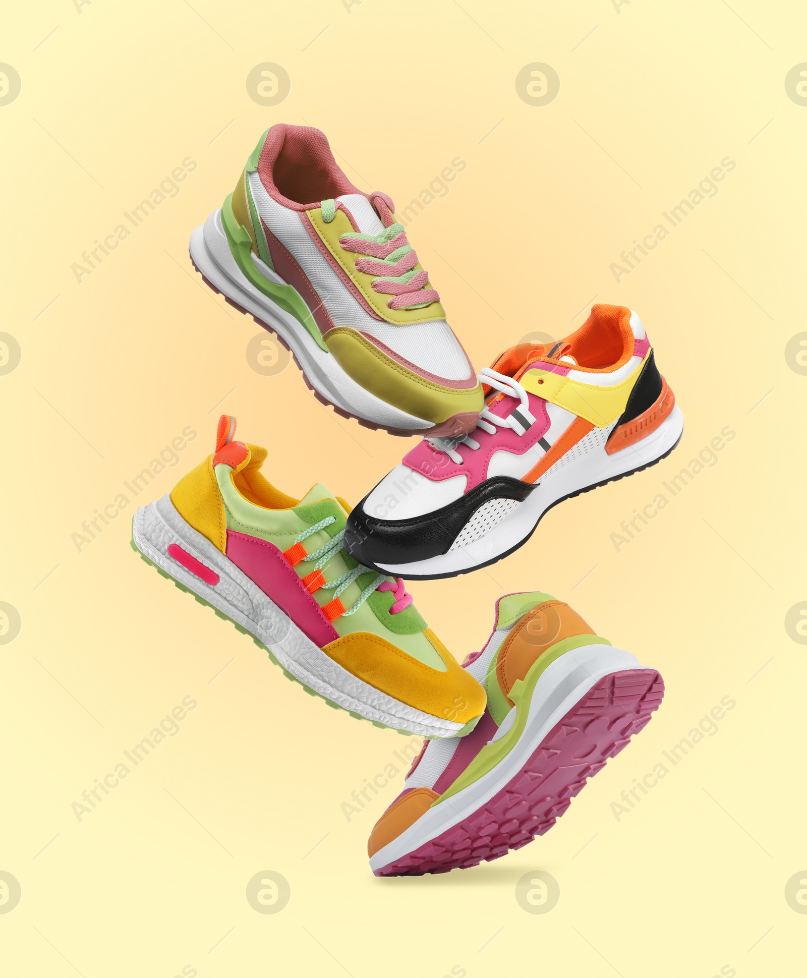 Image of Different sneakers falling on beige gradient background